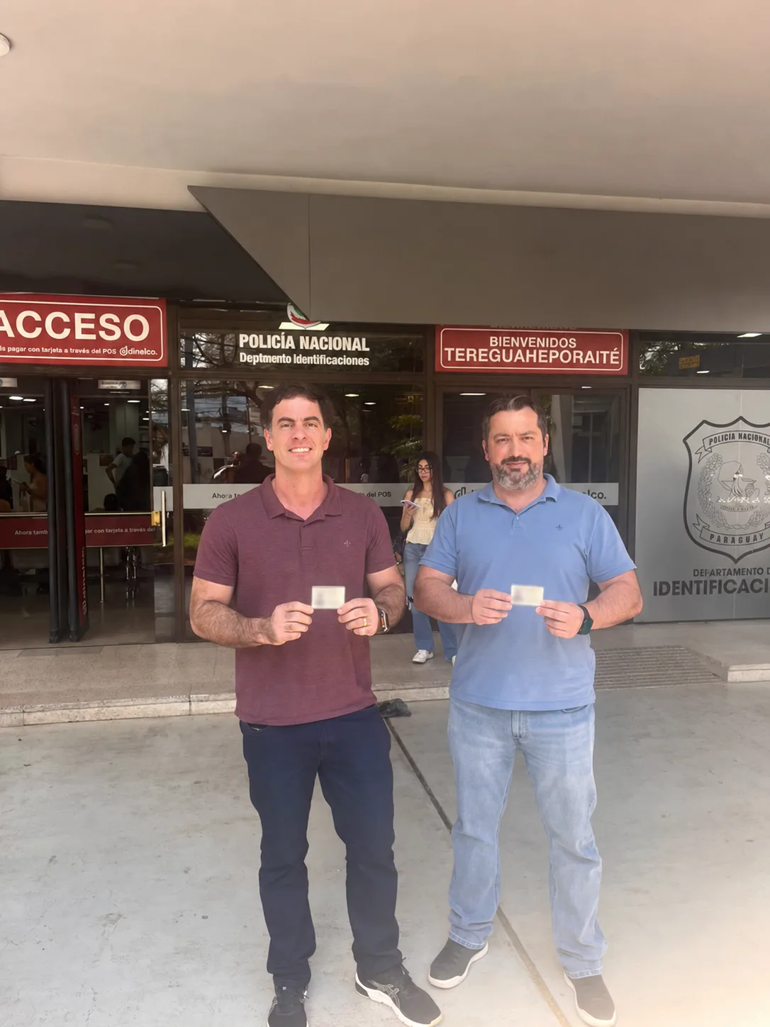 Felipe Calimam à esquerda e André Gustavo à direita, em frente ao Departamento de Identificações, com os dados das cédulas ocultados